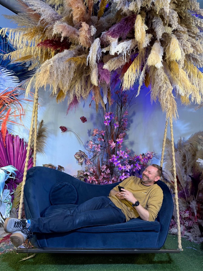 Andreas lachend auf einem blauen Samtsofa